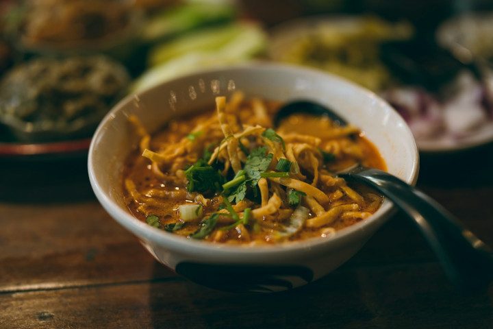 En skål khao soi med nudlar, curry och lime